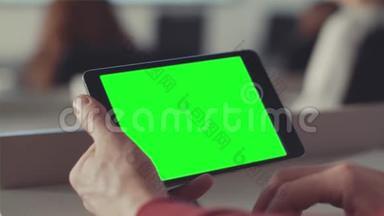 男人用绿色的屏幕看着平板电脑的屏幕。 库存。 手中平板电脑屏幕上的Chroma键